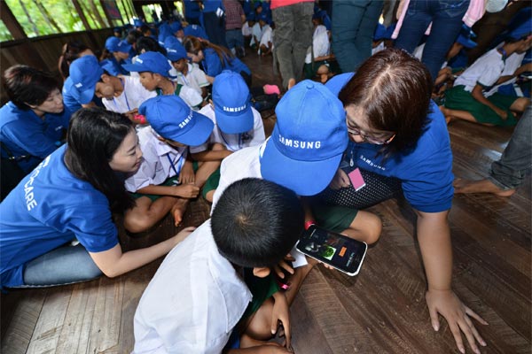 Samsung volunteers helping children with the alphabet game on Samsung tablets